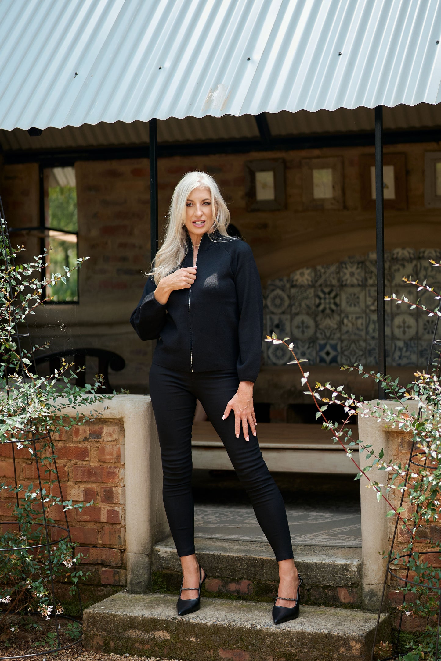 Black knitted zip-up jacket, showing ribbed collar, cuffs, and waistband with soft lighting.