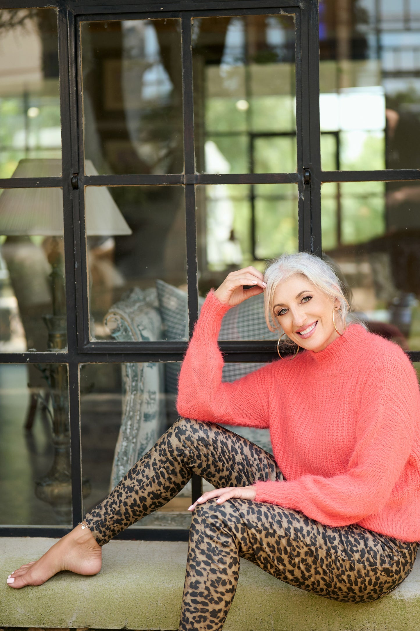 Model wearing ZADE Collection leopard print pleather pants and a coral mohair sweater, showcasing a bold animal print vegan leather look.