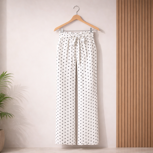 Women's white high-waisted wide leg palazzo pants with black polka dots, paperbag waist, adjustable tie belt and side pockets, styled for elegant casual and office wear.
