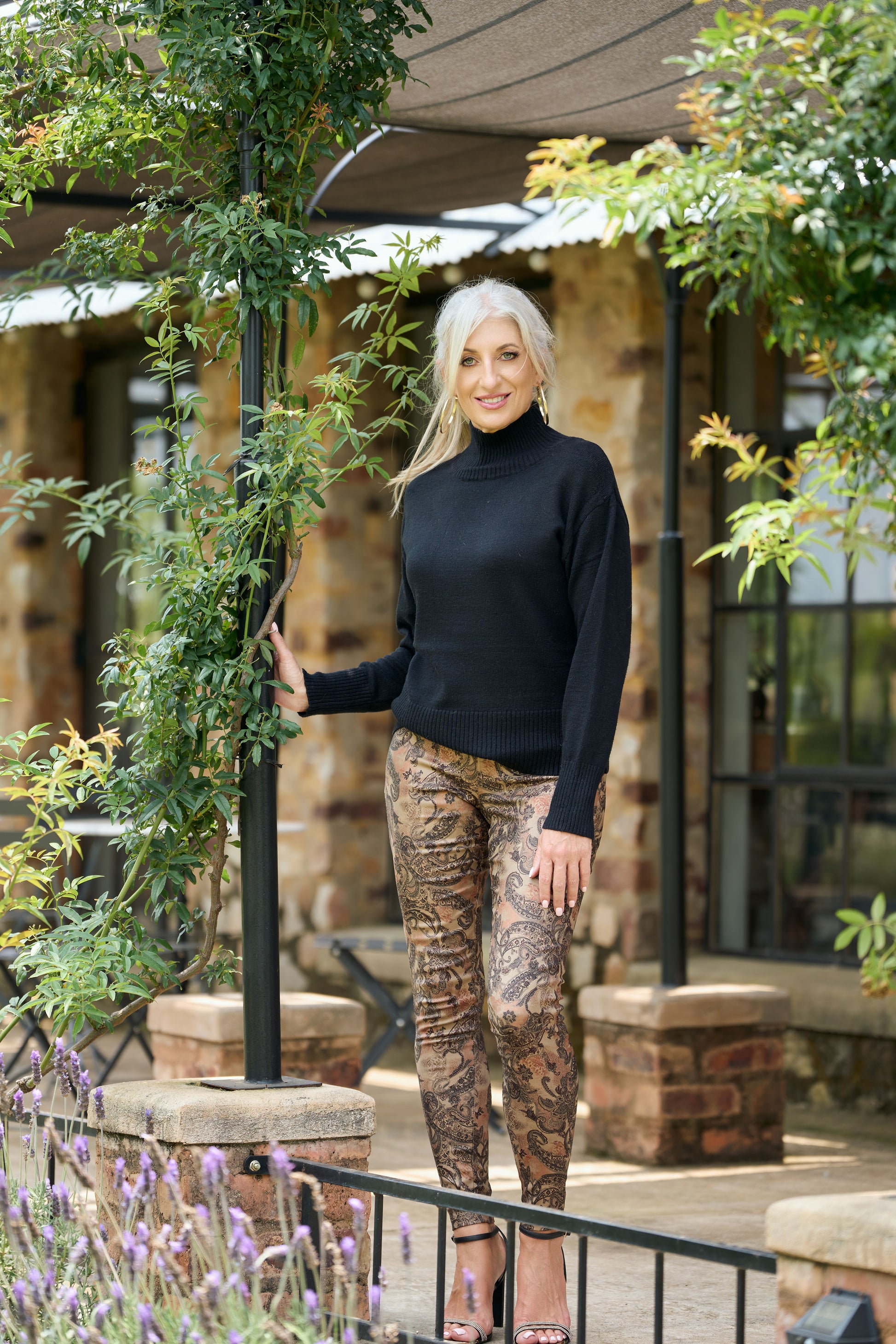 Women’s black poloneck sweater with long sleeves and fitted knit design styled with patterned pants – classic winter turtleneck fashion.