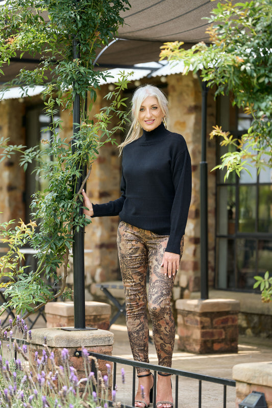 Women’s black poloneck sweater with long sleeves and fitted knit design styled with patterned pants – classic winter turtleneck fashion.