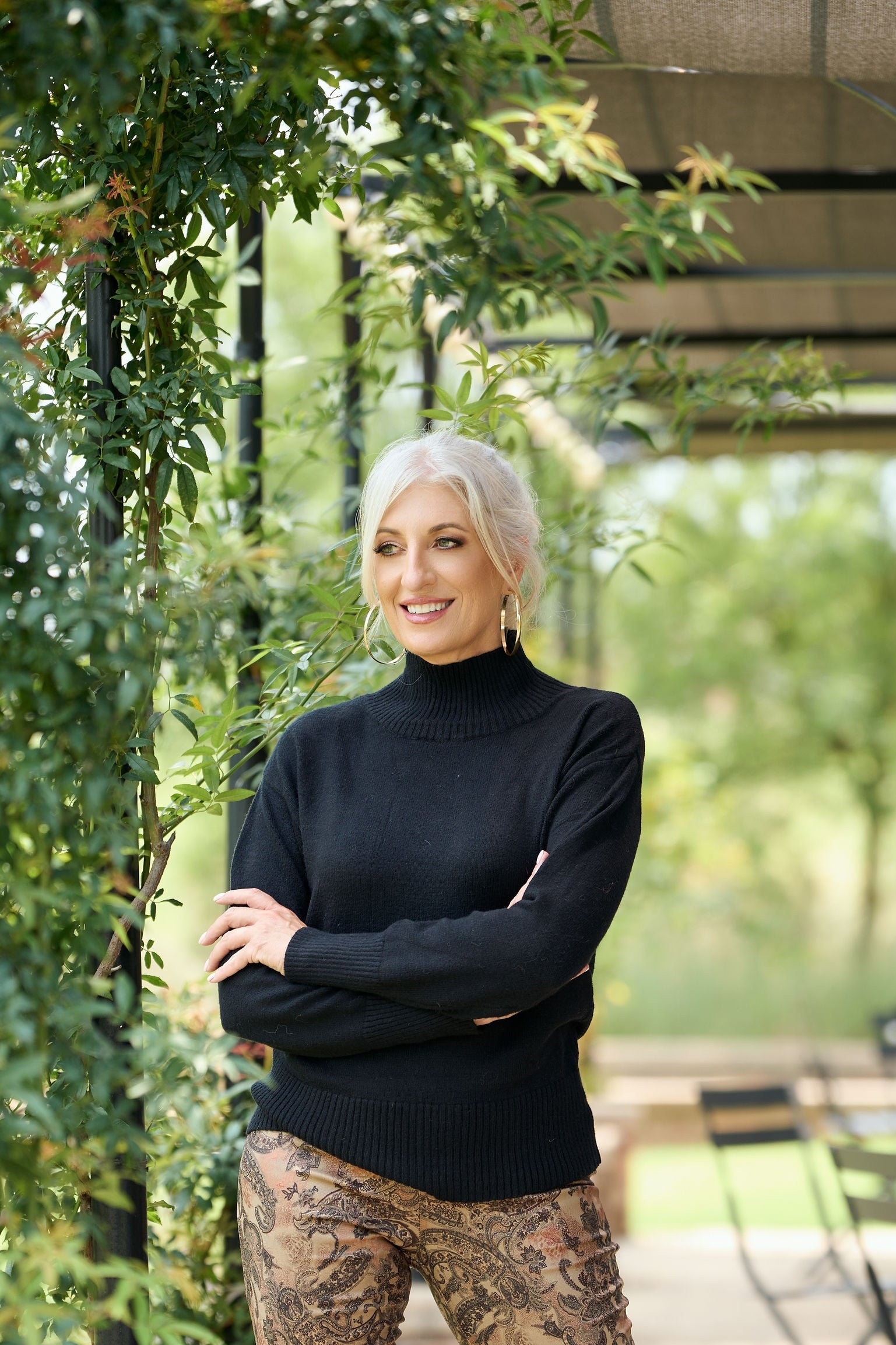 Women’s black poloneck sweater with long sleeves and fitted knit design styled with patterned pants – classic winter turtleneck fashion.